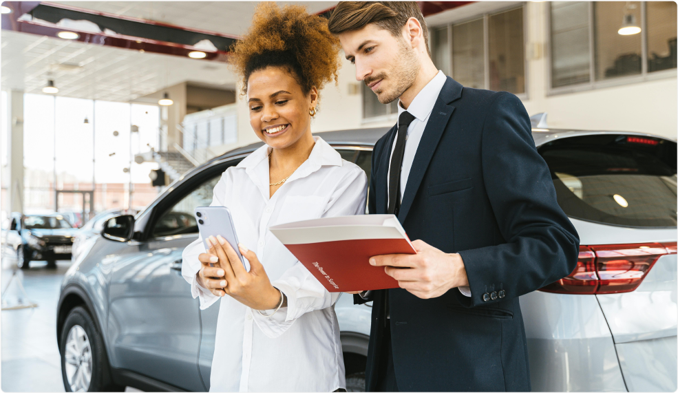 Auto dealer assisting a customer in a car showroom, reviewing auction details