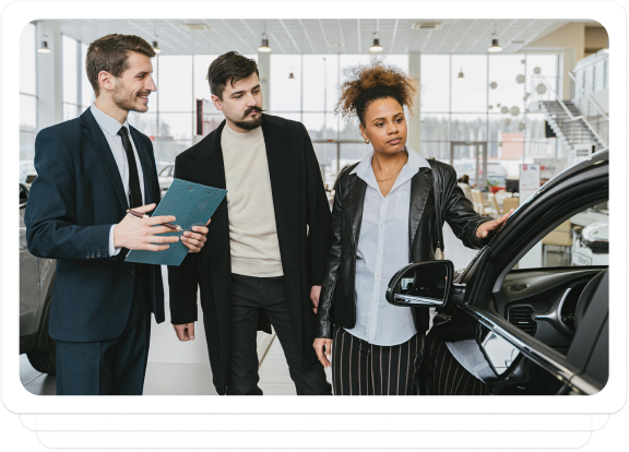 Auto dealer discussing vehicle details with customers in a showroom