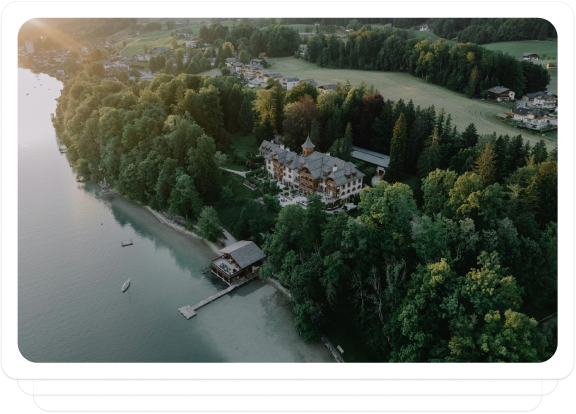 Aerial view of a lakeside property surrounded by lush greenery and waterfront access.