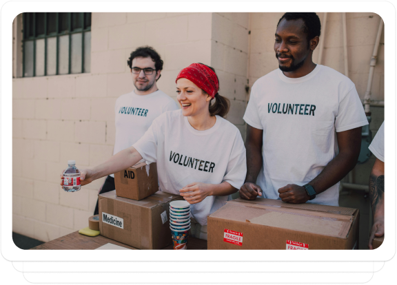 Volunteers handing out water bottles and aid boxes to support a fundraising campaign outdoors.